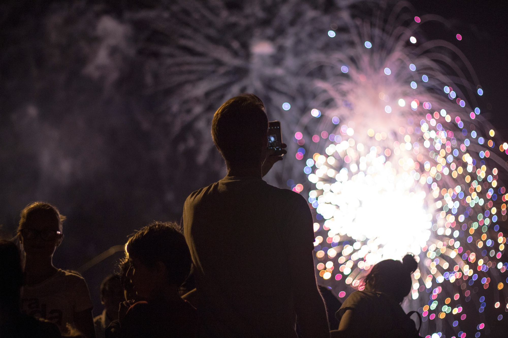 Spectateur filmant un feu d'artifice, l'émotion du spectacle